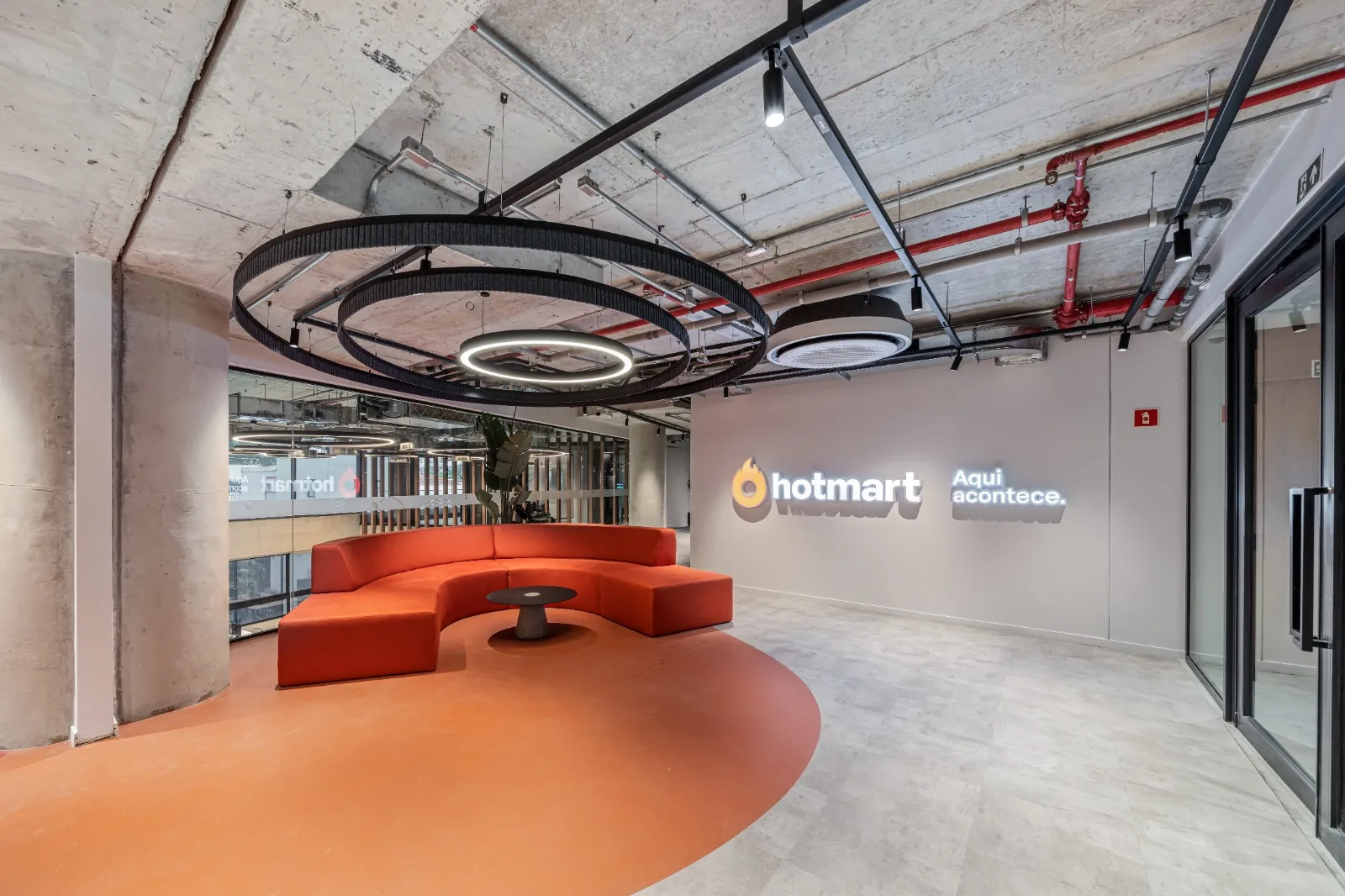 Lounge do Auditório Hotmart, com sofás curvos e pé-direito alto