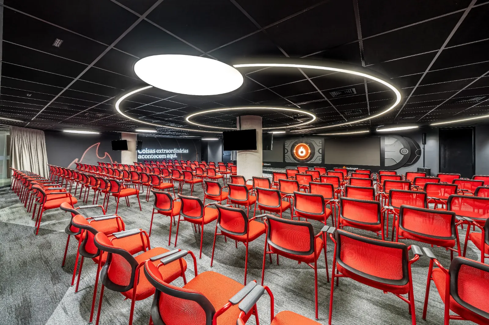 Auditório Hotmart montado em formato de plateia, com poltronas vermelhas e iluminação circular no teto